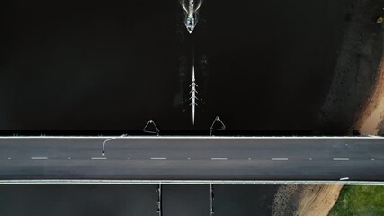 Aerial view of a rowing crew navigates under a bridge on a tranquil river during the serene morning hours - Powered by Adobe