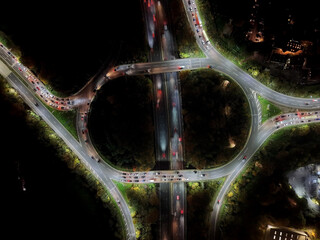 Aerial view over road traffic. Highway and overpass with cars and trucks, interchange, two-level road junction. Top view. Night shooting.