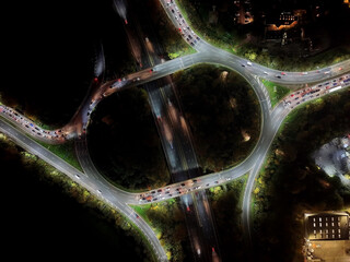 Aerial view over road traffic. Highway and overpass with cars and trucks, interchange, two-level road junction. Top view. Night shooting.