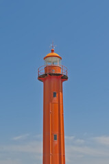 Sunny old red lighthouse along Tagus river on a blue sky in the harbour of Almada, Lisbon, Portugal