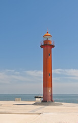 Fototapeta premium Old red lighthouse along Tagus river on a sunny day in the harbour of Almada, Lisbon, Portugal 
