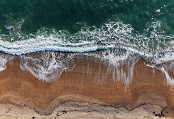 Aerial Top view of a transparent blue sea with beautiful waves at sunny day in summer. Tropical landscape from the air of ocean with azure water, sandy bottom at sunset. Aerial view of sand beach.