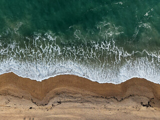 Aerial Top view of a transparent blue sea with beautiful waves at sunny day in summer. Tropical landscape from the air of ocean with azure water, sandy bottom at sunset. Aerial view of sand beach.