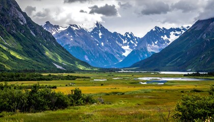 A sweeping vista showcases a vibrant green valley, leading towards towering, snow-capped peaks. Cloudy sky adds drama to this natural paradise