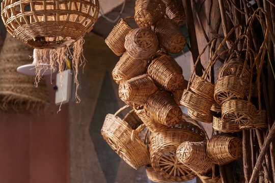 Rustic assortment of woven baskets hanging in a souk, showcasing authentic Moroccan craftsmanship. Handwoven wicker baskets and lamps displayed in a traditional Moroccan market stall.  - Powered by Adobe