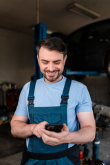 Mechanic checking his phone while working in an auto repair shop