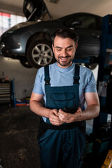 Mechanic checking phone while working on car in garage during the day