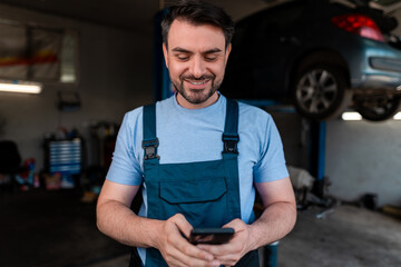 Mechanic checks phone while working in an auto repair shop during the day