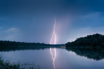 Beautiful lightning during thunderstorm at dusk over Sava river, lightning reflection on water...