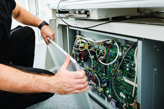 Engineer removing metal cover of medical x-ray unit for technical inspection and internal diagnostics during regular maintenance service.