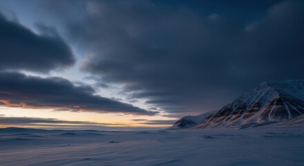 Expansive arctic tundra with snowcapped mountains. Winter wilderness during a dramatic polar sunset. Concept for adventure travel and environmental exploration. Cold remote nature