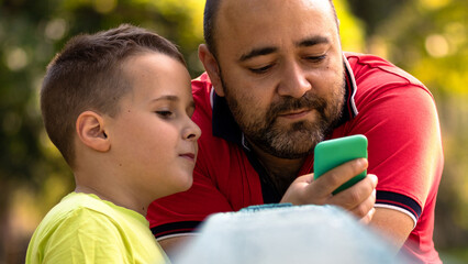 Father and son using a smartphone. A boy and a man looking at a mobile phone screen
