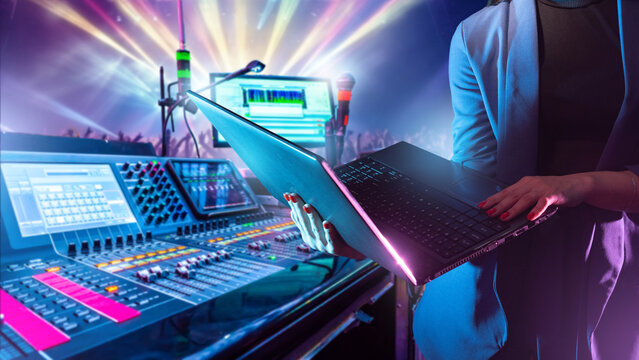 Sound engineer controls digital audio mixing and lighting systems during a live concert to ensure high-quality sound and stage performance.