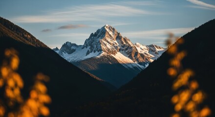 Majestic snow capped mountain peak at golden hour. Scenic alpine landscape with a deep valley. Wilderness travel and adventure tourism. Business success and reaching the summit concept