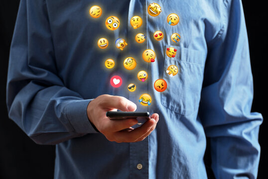 Man using smartphone sending emojis for social media communication