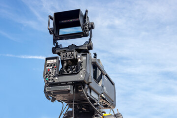 Professional camera on a massive tripod arm against a clear blue sky ready for film and tv production