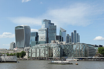 Obraz premium Modern skyscrapers line the Thames River in London showcasing urban architecture in bright daylight