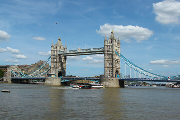 Obraz premium Tower Bridge stands tall over the River Thames on a sunny day in London with boats floating nearby