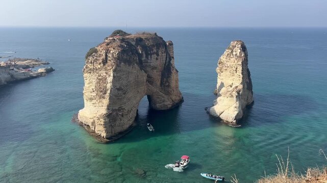 View of Pigeon Rocks on warm sunny day with tourist boats visiting the famous natural landmark just off the coast of Beirut, Lebanon.