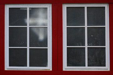 Two white lattice windows with dark red frames set in a red brick wall, highlighting a classic architectural feel.