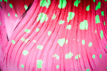 Texture of a wavy, bright pink fabric or surface with a pattern of green dots, highly vibrant and energetic.