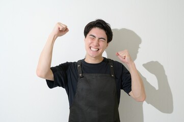 Fototapeta premium ガッツポーズをするエプロンをつけた日本人男性