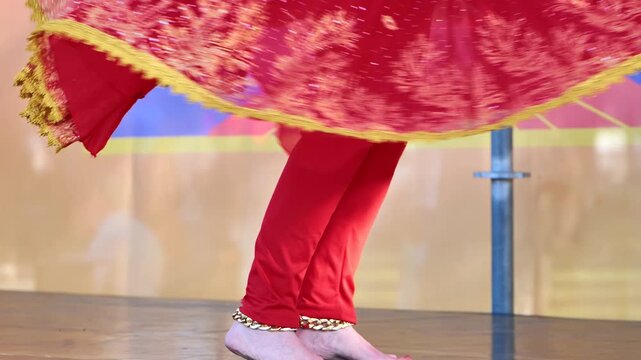 Indian dancer performing on stage wearing traditional red costume and ankle bells