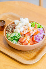 A gourmet poke bowl featuring scallops, shrimp, potato, cucumber, and quinoa rice, drizzled with parmesan cheese dressing and mustard vinaigrette. The dish presents a refreshing summer flavor with a b