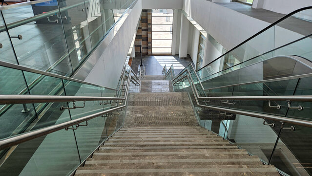 Bright stairway with glass and steel railings in modern business center, view from top