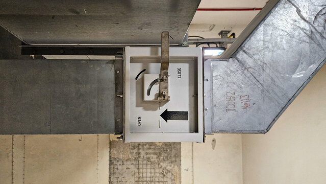 Close up of metallic air duct with open and close damper control in industrial ventilation system