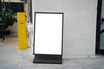 Blank white outdoor advertising stand sandwich board mock up template. Clear street signage board placed by an outdoor dinning area of a restaurant.