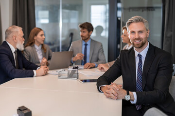 Portrait of businessman sitting at his desk in the office and smiling looking at camera