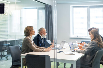 Creative business people, planning and meeting and brainstorming, ideas or strategy at office, view from glass wall.