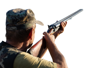 An adult hunter hunts in the autumn countryside. He fires a shotgun.