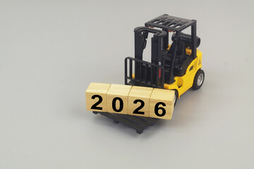 Forklift truck carrying wooden cubes with numbers 2026 on grey background. Copy space for text. Symbol of new year 2026.