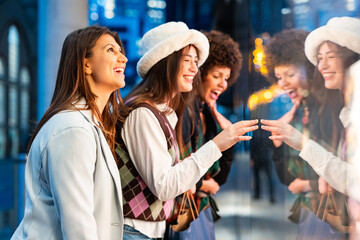 Women friends window shopping at city night