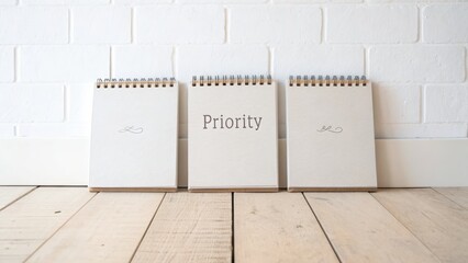 Three notebooks with priority word on a wooden table