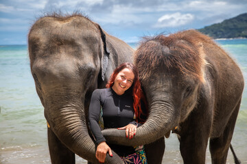  A beautiful girl and elephants. A girl with red hair. Big elephants.