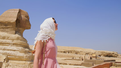 Woman exploring the Great Sphinx in Egypt, enjoying a sunny day of sightseeing during her vacation.
