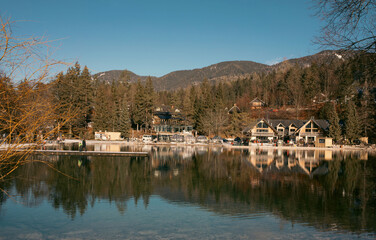 Obraz premium Kranjska Gora, Slovenia - January 04, 2024: Scenic view of tranquil Jasna lake reflecting mountains and charming lodges in Triglav National Park, showcasing the beauty of the Julian Alps landscape