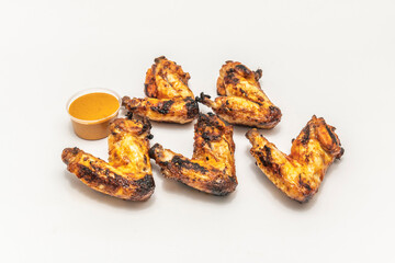 Fried chicken wings coated in a spicy mango and tamarind sauce, presented on a banana leaf with a side of tropical salad