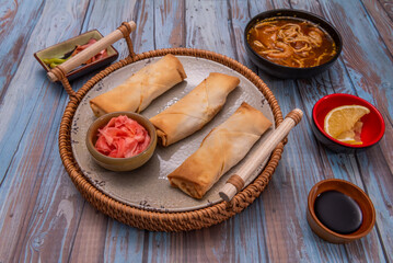 Still life with vegetarian spring rolls showing their cabbage and mushroom filling, accompanied by creamy peanut sauce and garnished with freshly chopped chives