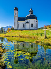 Obraz premium Seekirche Heiliges Kreuz, Seefelder Seekirchl, spiegelt sich im Wasser des Raabach, Seefeld, Tirol, Österreich, Europa