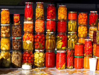 Colorful jars of pickled vegetables stacked on a market table for sale