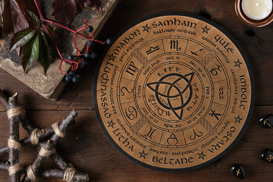 Mystic Wheel of the Year with runes and ritual items on a wooden table. Spiritual and pagan concept.