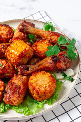 Fried chicken drumsticks, Mexican style, with corn, on a plate, close-up,