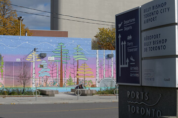 Fototapeta premium ironical mural of trees at a school and signs at Billy Bishop Toronto City Airport Terminal, near 2 Eireann Quay