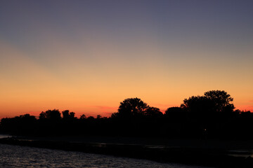 Twilight view of a calm shoreline with silhouetted trees