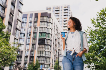 Young woman walking in the city with a coffee smiling stylish casual modern urban lifestyle on a sunny day
