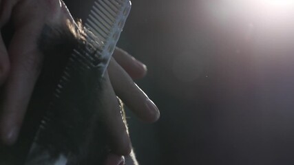 A professional barber uses sharp scissors and a comb for precise hair trimming around the ear. Close-up detail of the salon cutting process.